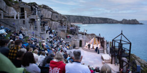 Audience watching an open air performance with sea in background